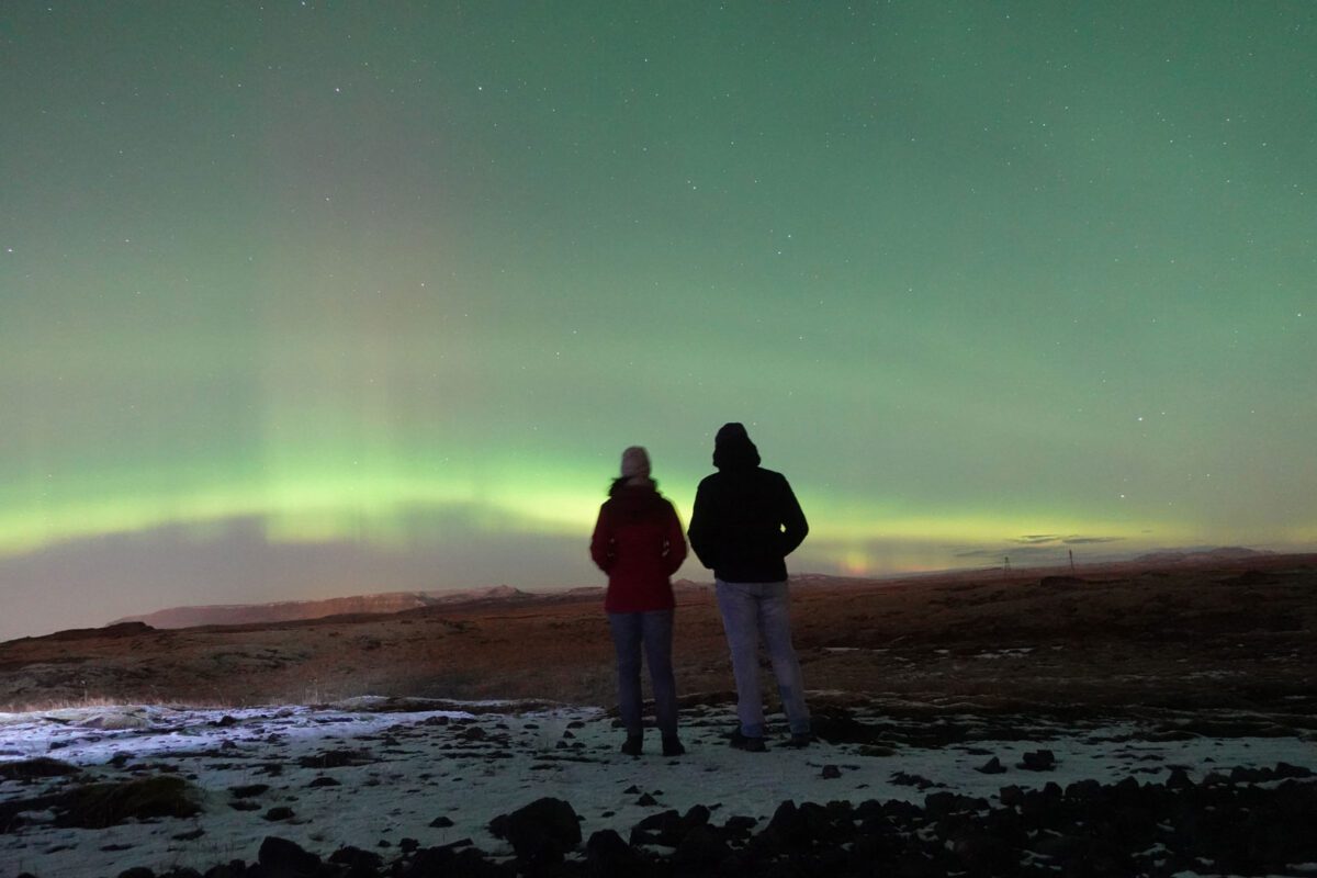 two people facing the northern lights in iceland