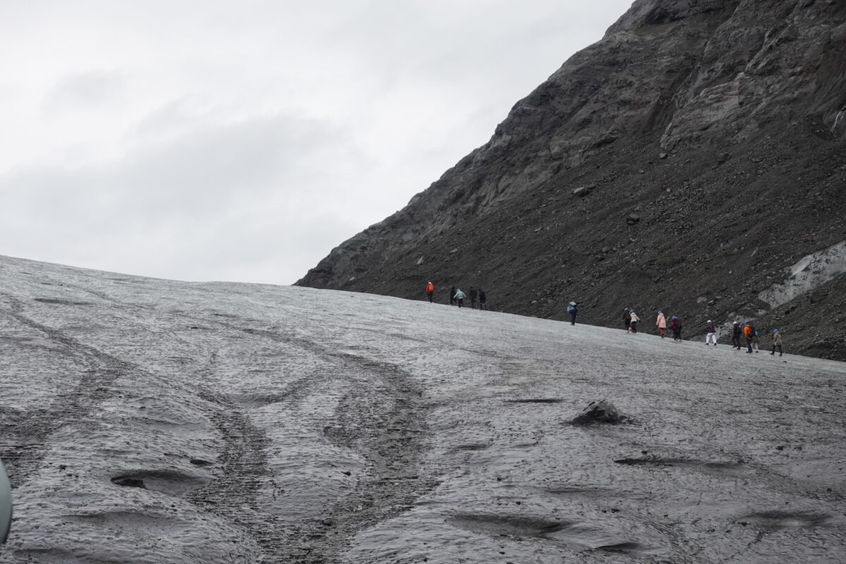 a group of people walking in a line on a glacier hiking tour in iceland